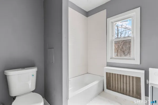 a white toilet sitting next to a bath tub