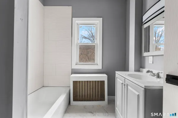a bathroom with a tub sink and mirror
