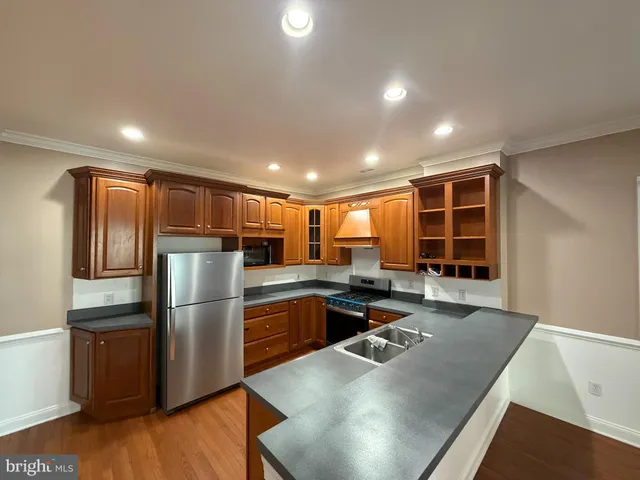 a kitchen with stainless steel appliances granite countertop a refrigerator a sink and a stove