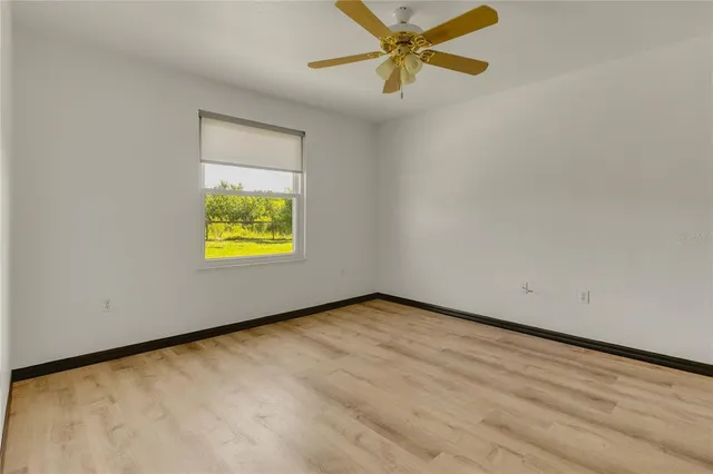 an empty room with a window and a ceiling fan