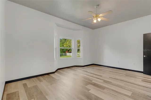 an empty room with a window and a ceiling fan