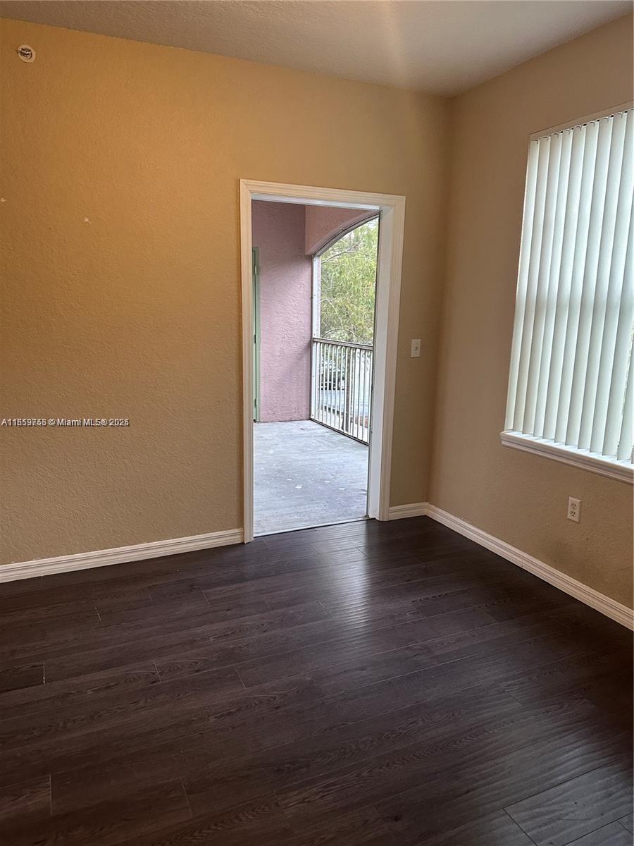 6790 West Sample Road, Unit 6790 Coral Springs, FL 33067 - Photo 12 of 26 a view of an empty room with wooden floor and a window