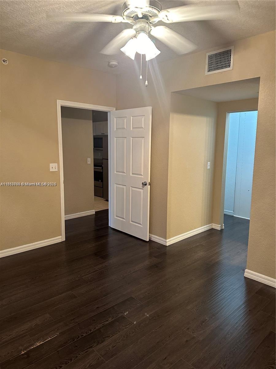 6790 West Sample Road, Unit 6790 Coral Springs, FL 33067 - Photo 18 of 26 an empty room with wooden floor chandelier fan and windows