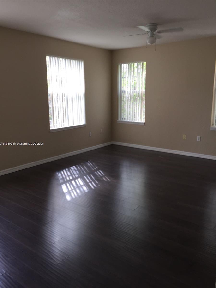 6790 West Sample Road, Unit 6790 Coral Springs, FL 33067 - Photo 6 of 26 an empty room with wooden floor and windows