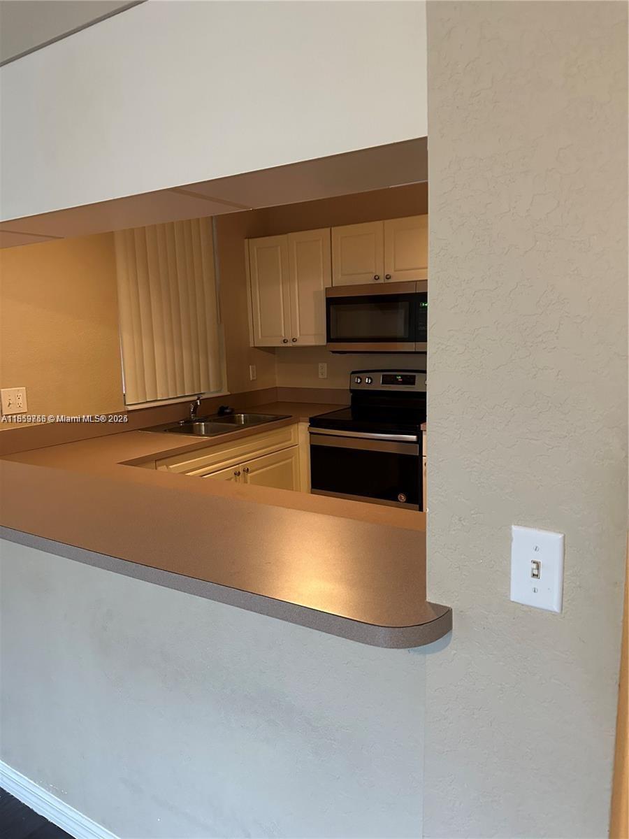 6790 West Sample Road, Unit 6790 Coral Springs, FL 33067 - Photo 9 of 26 a kitchen with stainless steel appliances a stove a microwave and a sink