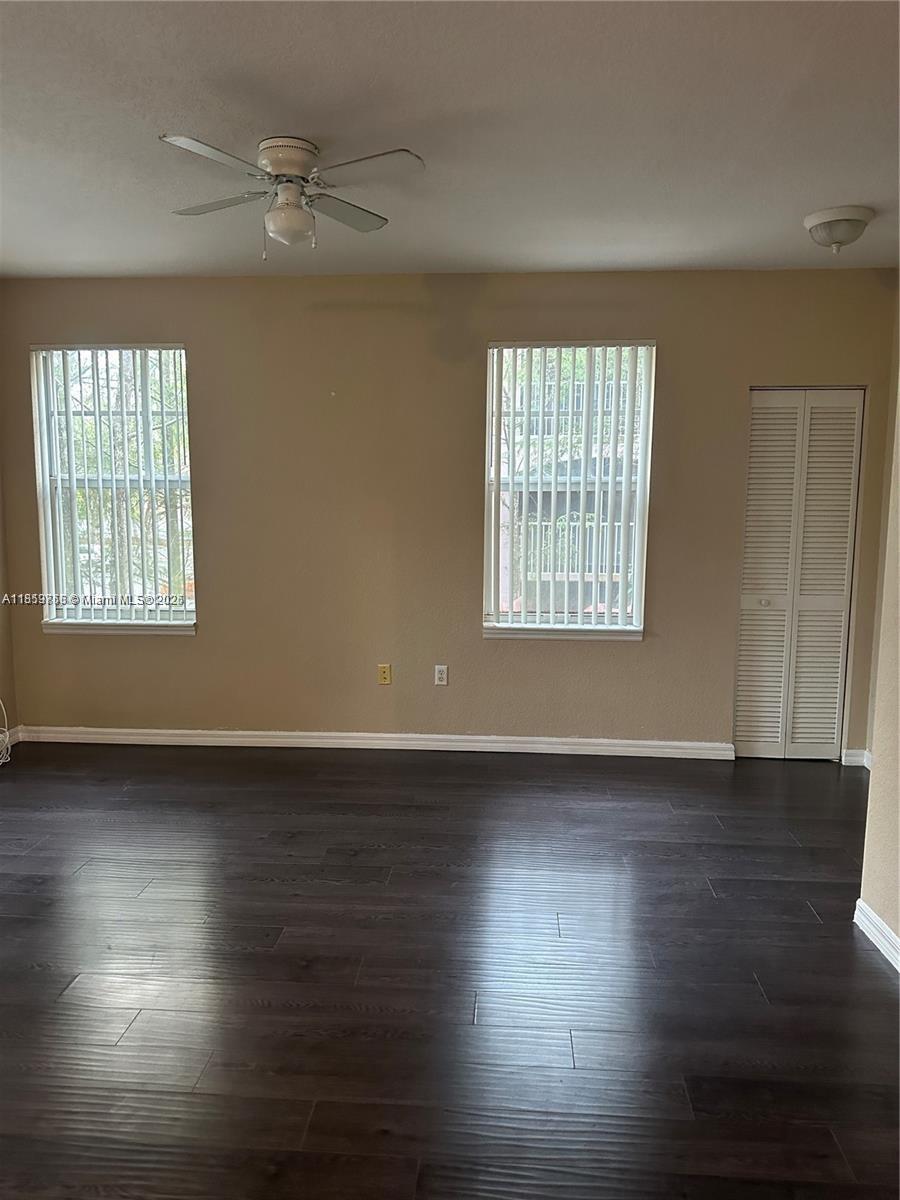 6790 West Sample Road, Unit 6790 Coral Springs, FL 33067 - Photo 10 of 26 an empty room with wooden floor chandelier fan and windows