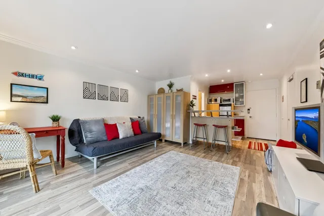 a living room with furniture kitchen view and a wooden floor