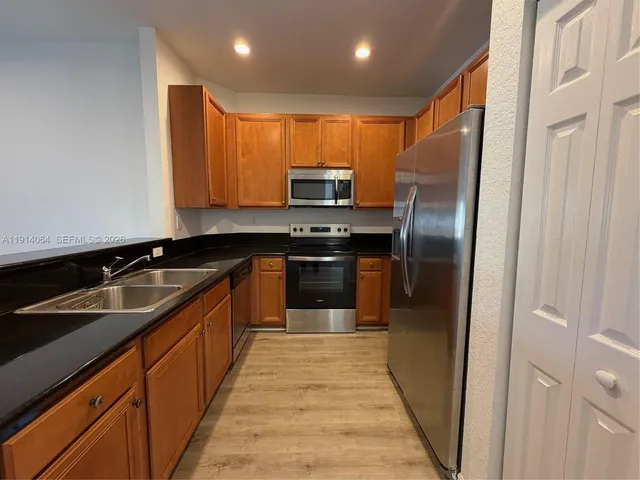 a kitchen with stainless steel appliances granite countertop a refrigerator and a sink