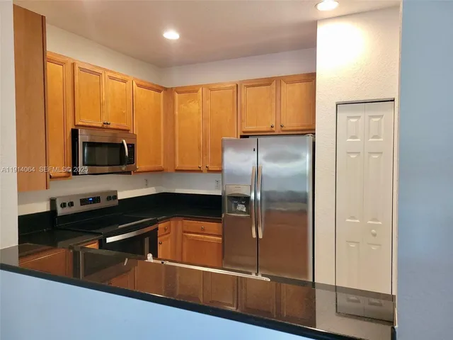 a kitchen with granite countertop a refrigerator a sink a stove and cabinets
