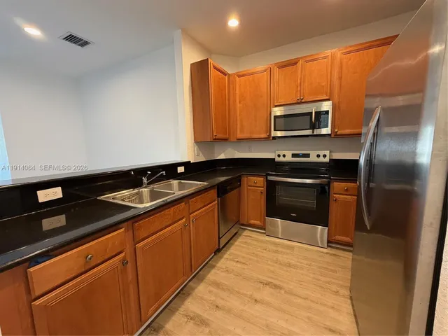 a kitchen with stainless steel appliances granite countertop a sink stove microwave and refrigerator