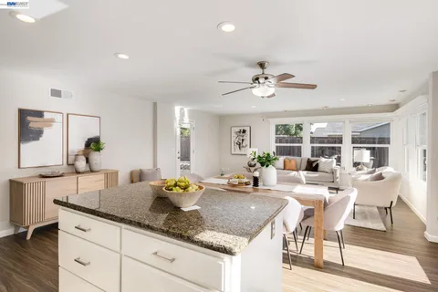 a kitchen with granite countertop a dining table chairs and white cabinets