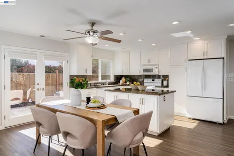 a kitchen with stainless steel appliances granite countertop a dining table chairs refrigerator microwave and cabinets