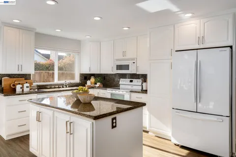 a kitchen with granite countertop white cabinets and white appliances