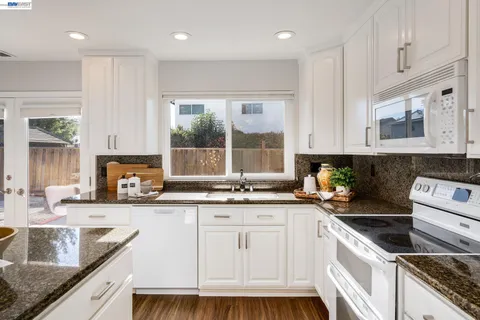 a kitchen with granite countertop a sink a stove and cabinets