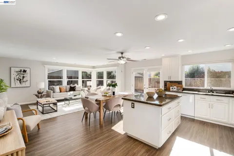 a living room with stainless steel appliances granite countertop furniture and wooden floor