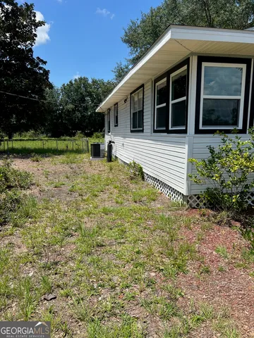 a backyard of a house with large trees and plants