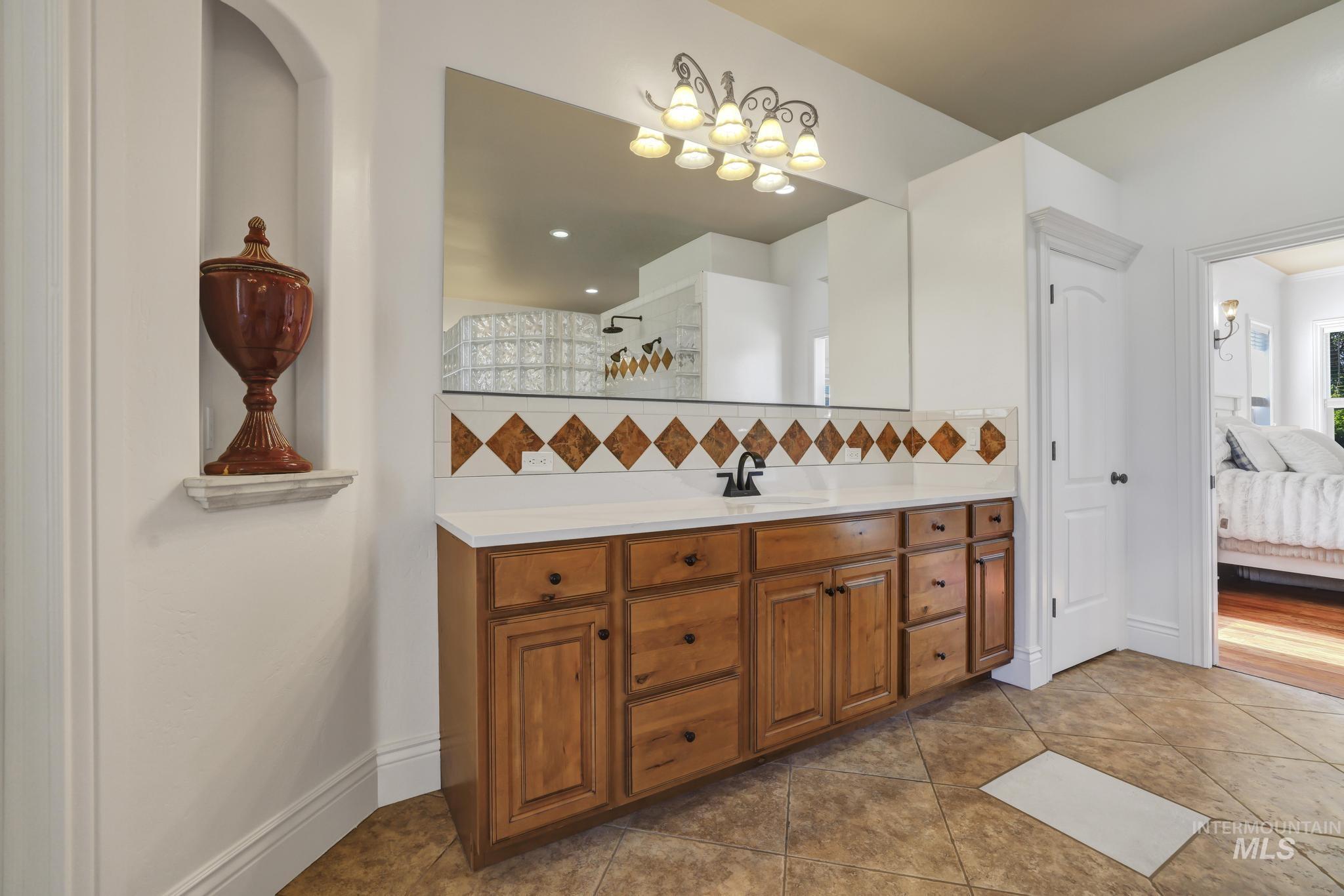 1301 Kanaka Rapids Road Buhl, ID 83316 - Photo 23 of 50 Large vanity with wood-finish cabinetry, white countertop, and diamond-patterned tile backsplash