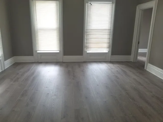 an empty room with wooden floor and windows