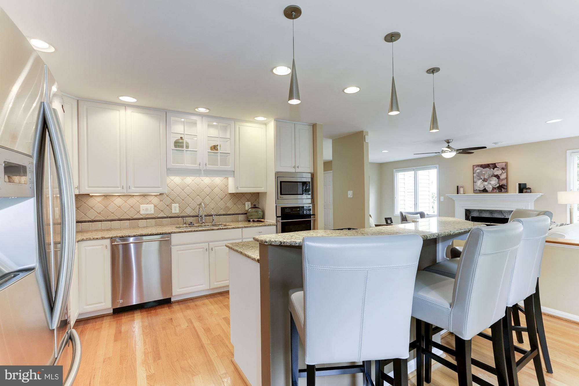 1311 Pavilion Club Way Reston, VA 20194 - Photo 12 of 28 a kitchen with stainless steel appliances kitchen island granite countertop a table chairs sink and cabinets