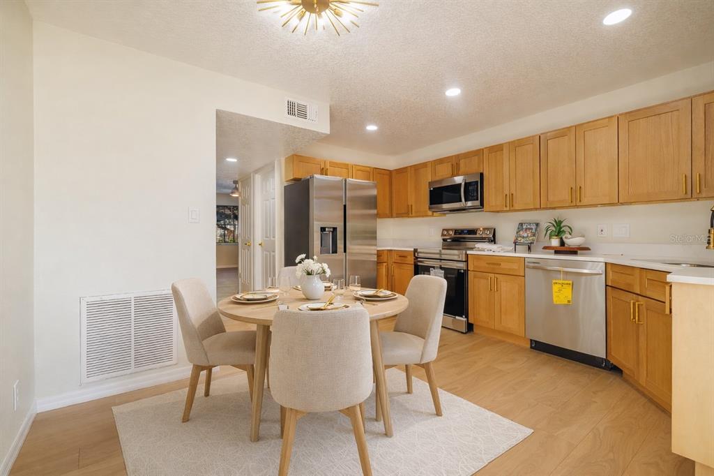 6922 Woodlake Drive, Unit 103 Orlando, FL 32810 - Photo 4 of 16 a kitchen with a dining table chairs and white cabinets