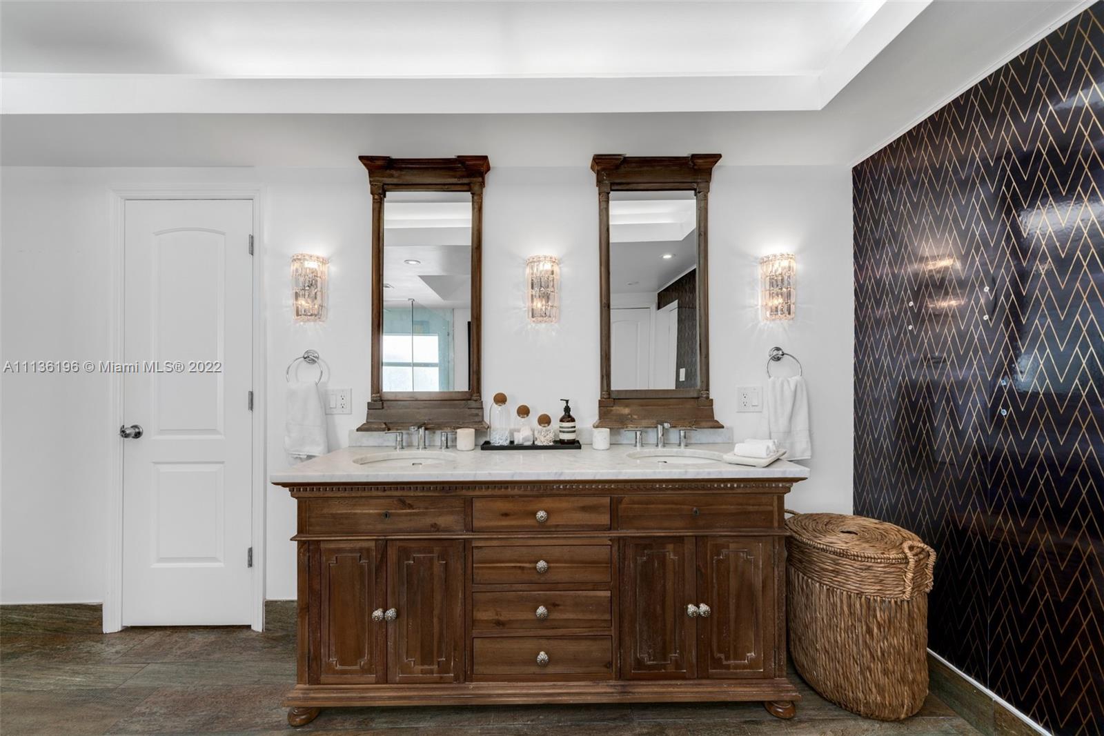5852 Pine Tree Drive Miami Beach, FL 33140 - Photo 25 of 53 a bathroom with a double vanity sink and mirror