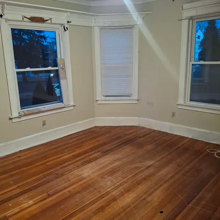 a view of empty room with window and wooden floor