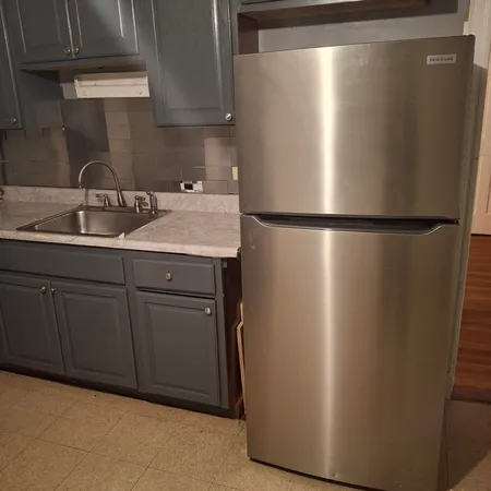 a view of a refrigerator in kitchen and a sink
