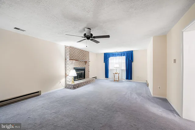 a view of an empty room with a fireplace and a window