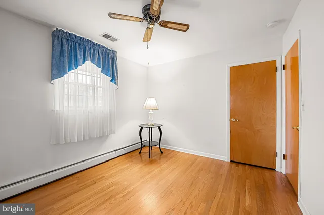 a view of a room with wooden floor a ceiling fan and windows