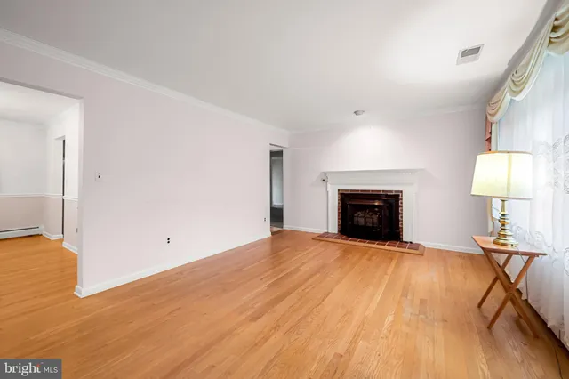 a view of empty room with wooden floor and fireplace