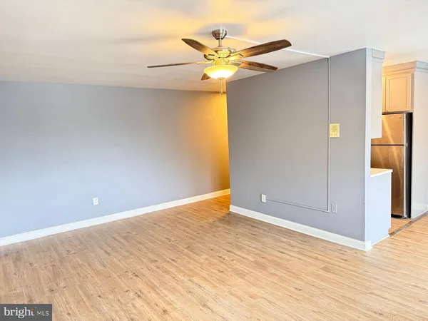 a view of an empty room with wooden floor and a ceiling fan