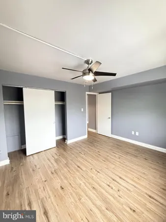 a view of an empty room with wooden floor and a ceiling fan