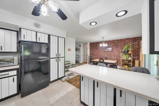 a kitchen with stainless steel appliances kitchen island granite countertop a refrigerator a sink a stove and a dining table with wooden floor