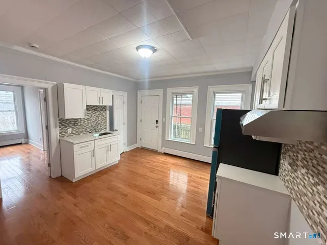 a large kitchen with granite countertop a stove a sink dishwasher and a refrigerator with wooden floor