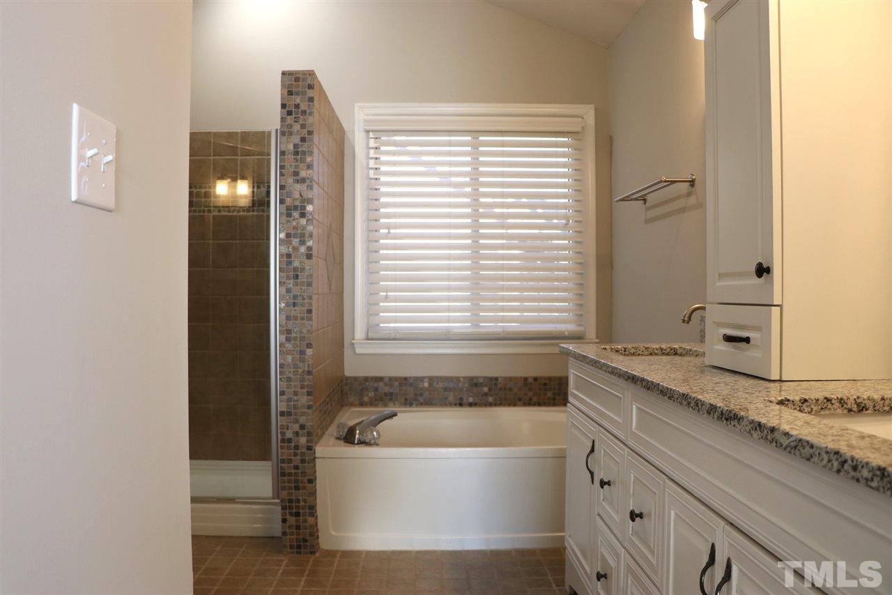 5713 Edgebury Road Raleigh, NC 27613 - Photo 16 of 26 a bathroom with a granite countertop tub and a sink