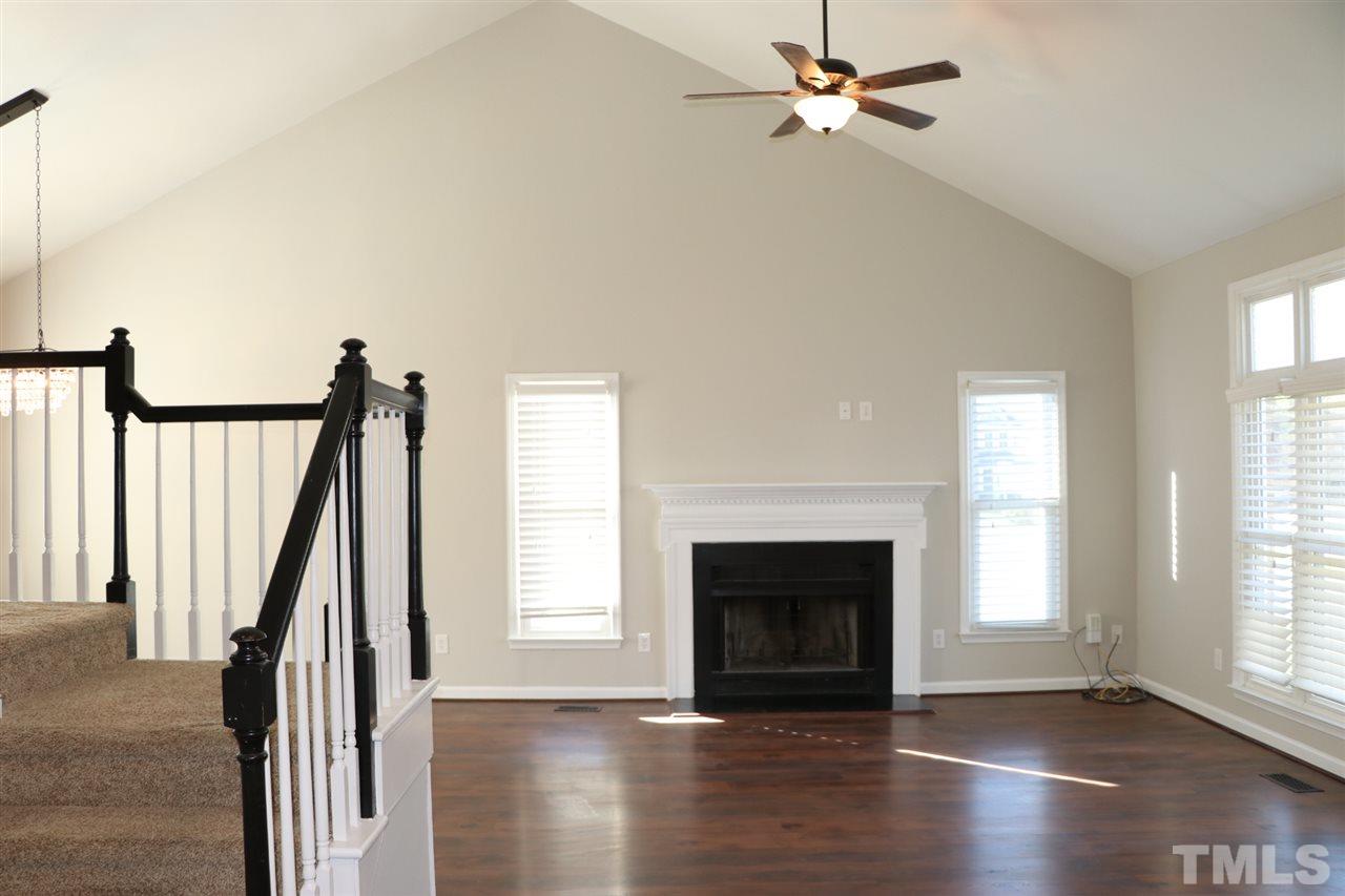 5713 Edgebury Road Raleigh, NC 27613 - Photo 4 of 26 an empty room with windows fireplace and wooden floor