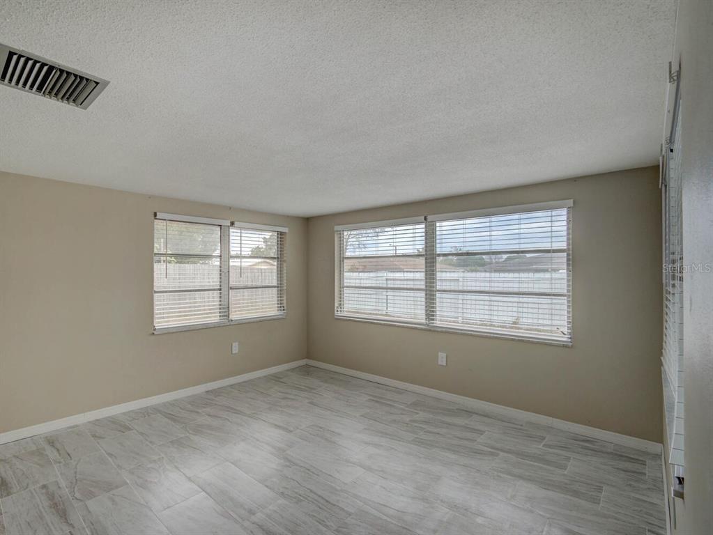 10320 Honeysuckle Lane Port Richey, FL 34668 - Photo 7 of 53 a view of an empty room with wooden floor and a window