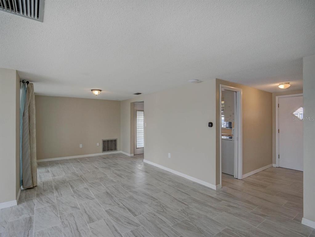 10320 Honeysuckle Lane Port Richey, FL 34668 - Photo 9 of 53 a view of an empty room with wooden floor and a window