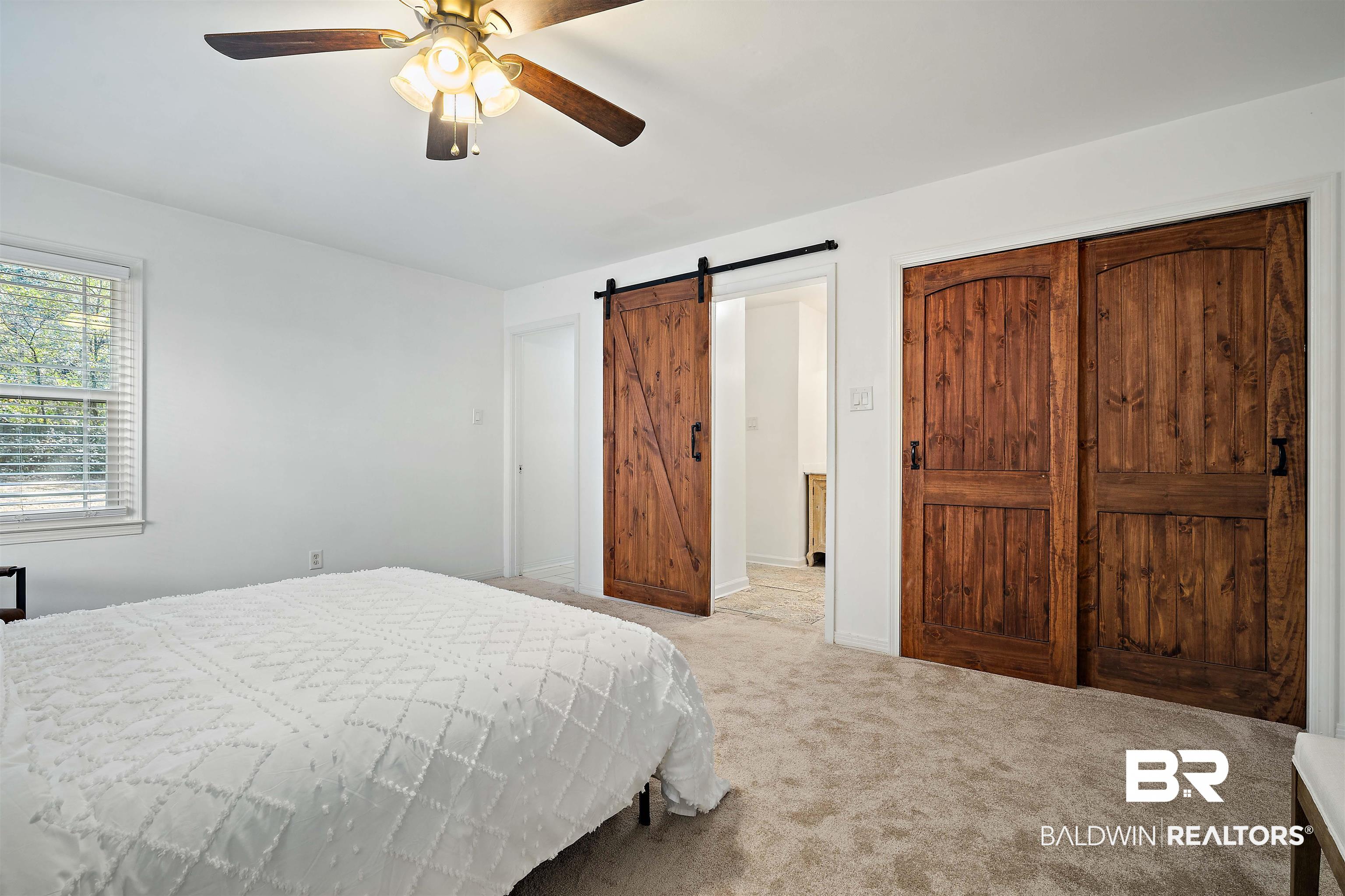 2615 Walton Avenue Mobile, AL 36606 - Photo 20 of 33 Bedroom featuring a closet, a barn door, a ceiling fan, carpet flooring, and baseboards