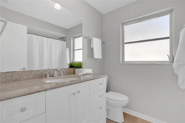 a bathroom with a granite countertop sink toilet and mirror