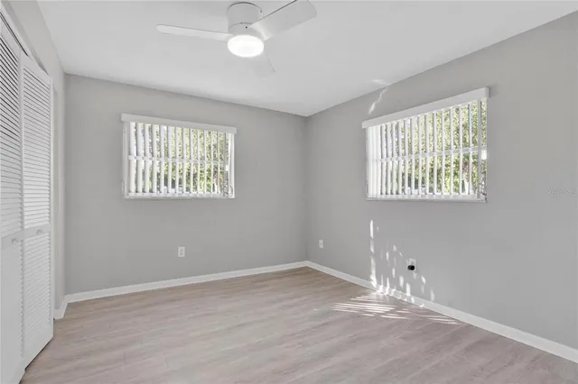 an empty room with wooden floor and windows