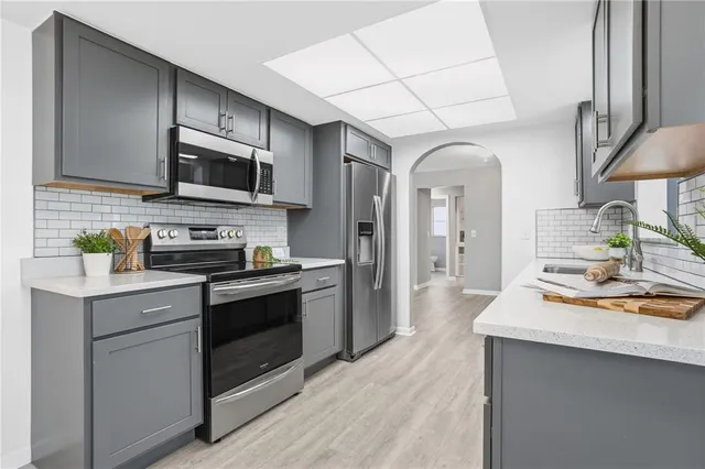 a kitchen with stainless steel appliances a sink cabinets and wooden floor