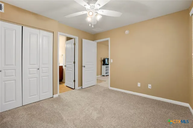 an empty room with closet and a chandelier fan