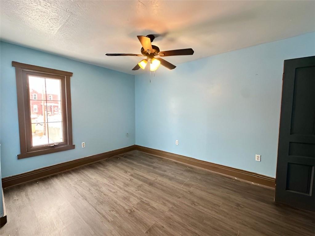 910 9th Avenue Beaver Falls, PA 15010 - Photo 9 of 11 an empty room with wooden floor fan and windows