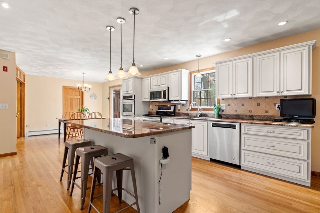 628 Boston Road Groton, MA 01450 - Photo 3 of 32 a kitchen with stainless steel appliances granite countertop a stove top oven a refrigerator a sink and white cabinets with wooden floor