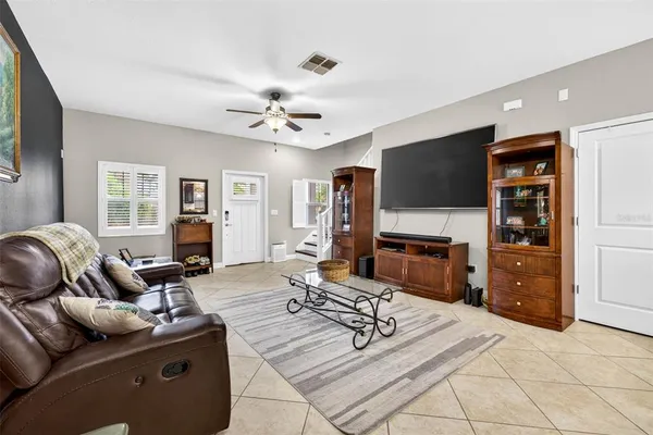 a living room with furniture a flat screen tv and a refrigerator