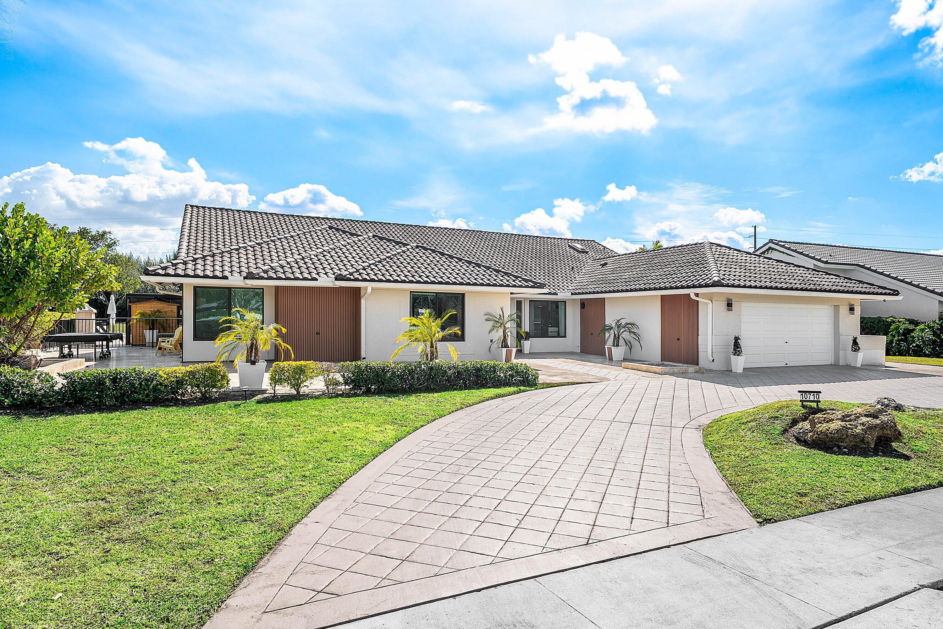 10710 Boca Woods Lane Boca Raton, FL 33428 - Photo 22 of 44 a front view of a house with a garden and yard