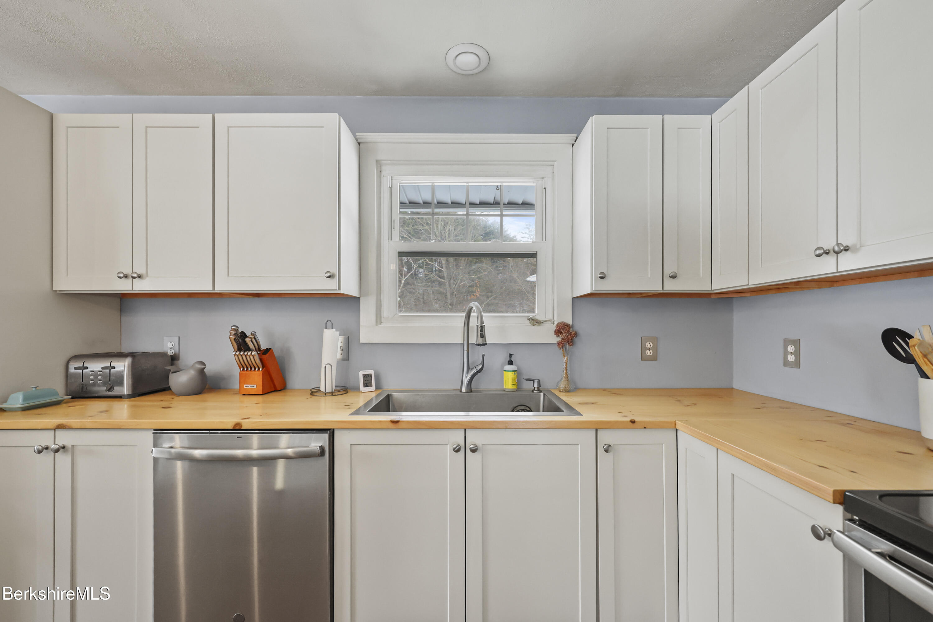 184 Washington Mountain Road Lee, MA 01238 - Photo 18 of 42 a kitchen with stainless steel appliances granite countertop a sink a stove and white cabinets