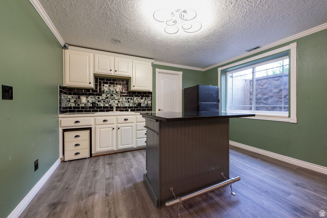 875 East 1300th Street North Mapleton, UT 84664 - Photo 38 of 65 Two tone kitchen featuring dark countertops, ornamental molding, freestanding refrigerator, a center island, and backsplash