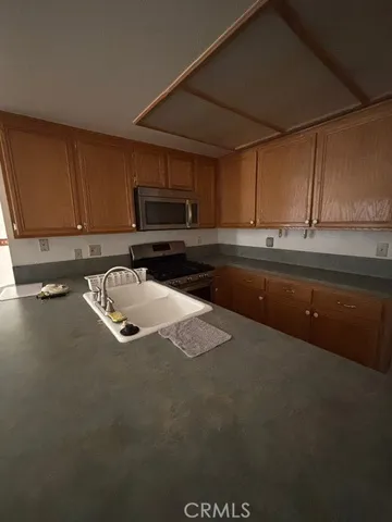 a kitchen with kitchen island a sink a stove and cabinets